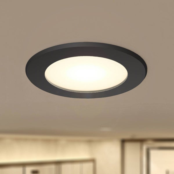 Runder schwarzer LED-Einbaustrahler mit warmweißem Licht an der Decke montiert.