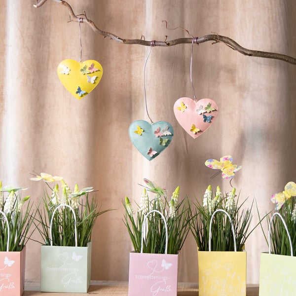 Dekoherzen mit Schmetterlingen zum Aufhängen und frühlingshafte Pflanztüten mit Blumendekoration für die Frühlingsdekoration.
