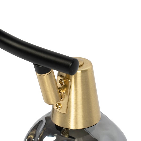 Detailansicht einer Lampe mit schwarzem Arm und goldfarbenem Lampenkopf