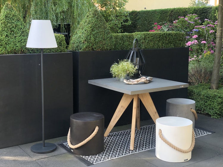 Dekorative Pflanzgefäße aus Beton mit Seilgriffen und eine schwarze Laterne mit Kerze