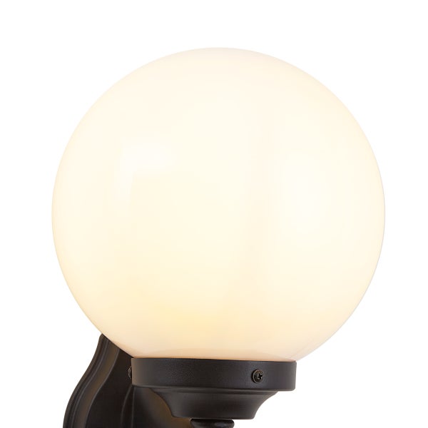 Wandleuchte mit weißer Glaskugel und dunklem Metallsockel für den Außenbereich.