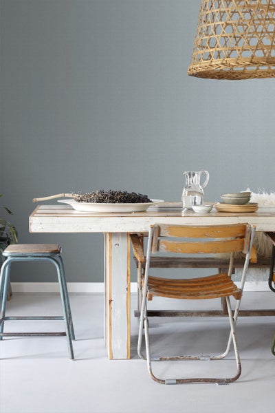 Esszimmer mit Holztisch, Stühlen, Hocker und Lampe aus Korbgeflecht