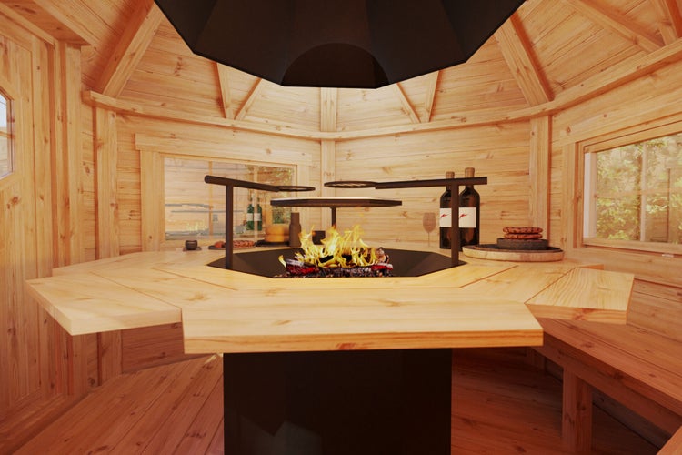 Innenansicht eines Grillkota mit Grillstelle, Tisch und Sitzbänken aus Holz