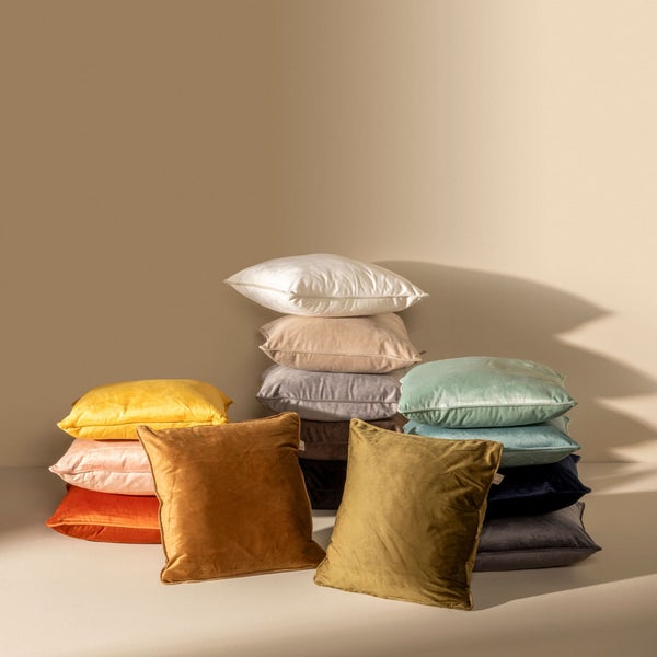 Stapel dekorativer Kissen aus Samt in verschiedenen Farben.