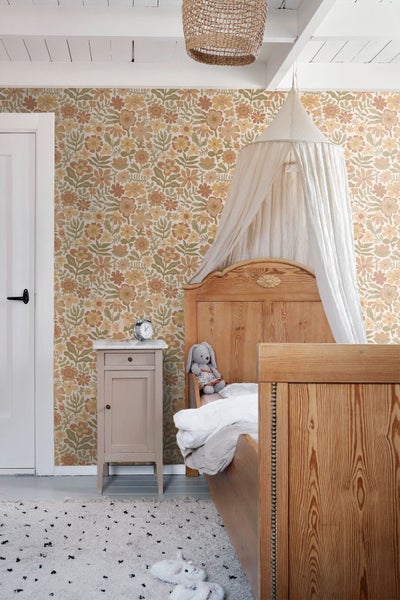Kinderzimmer mit floraler Vliestapete im Vintage-Stil, Holzbett mit Betthimmel und kleinem Nachttisch.