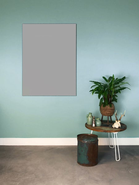 Ein modern gestalteter Raum mit türkisgrüner Wandfarbe, einem grauen Wandelement, einem runden Beistelltisch und einer Zimmerpflanze.