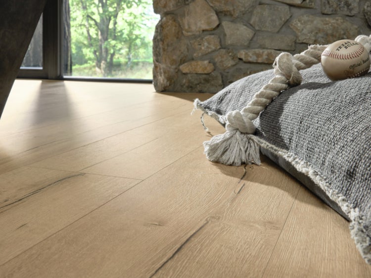 Holzoptik Laminatboden in einem Wohnraum mit Natursteinwand Akzenten und einem Kissen auf dem Boden