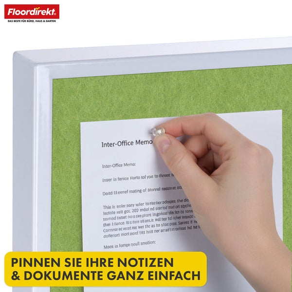 Grüne Pinnwand mit weißem Rahmen, eine Hand befestigt eine Notiz mit einer Reißzwecke