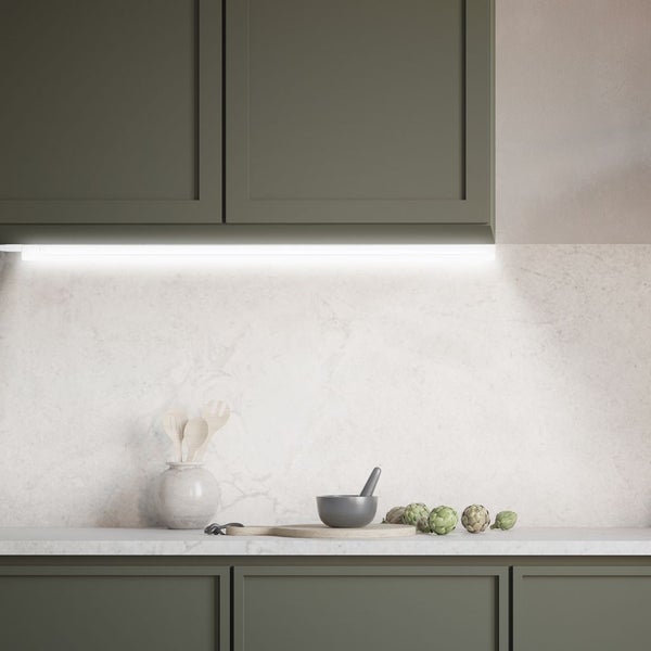 Küchenszene mit Unterschrank, Hängeschrank, Arbeitsplatte, Beleuchtung, Mörser, Artischocken und Holzlöffeln