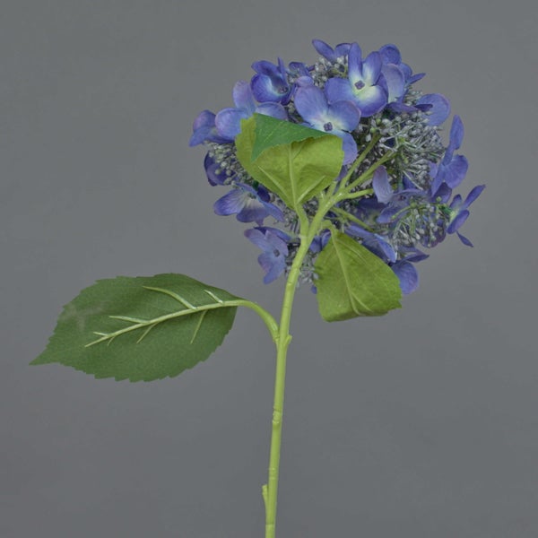 Künstliche Hortensie mit blauen Blüten und grünen Blättern.