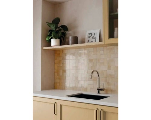 Moderne Küchenszene mit beige glasierten Fliesenspiegel-Fliesen im Muster, einer Chrom-Armatur, schwarzer Spüle und hellen Schränken.