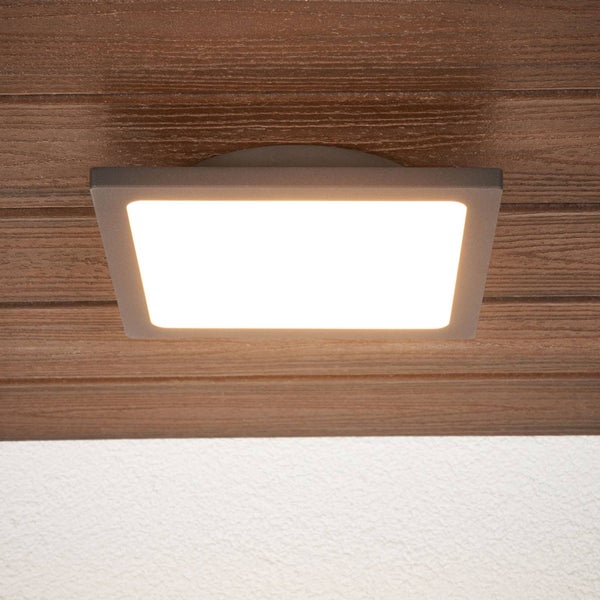 Quadratische LED-Anbauleuchte in Anthrazit, montiert an einer braunen Holzdecke, strahlt warmweißes Licht aus.