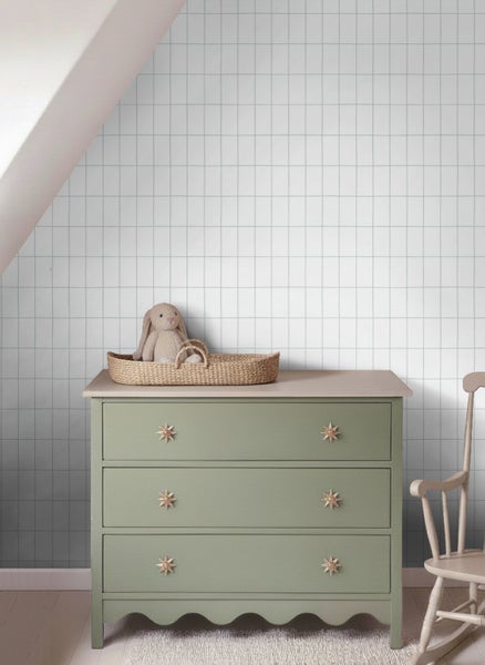 Vliestapete mit feinem Gittermuster in einem hellen, organisierten Kinderzimmer hinter einer Kommode aus Holz.