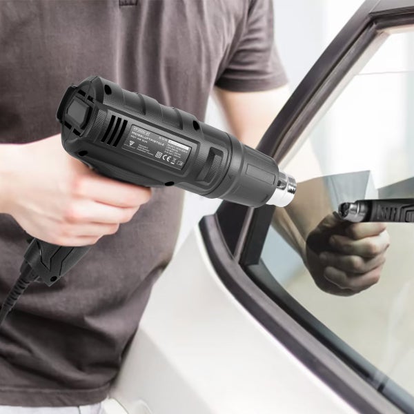 Eine Person verwendet eine Heißluftpistole an einem Autofenster.