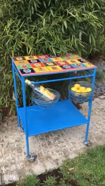 Servierwagen mit farbenfroher Tischplatte, Flasche und Zitronen im Garten