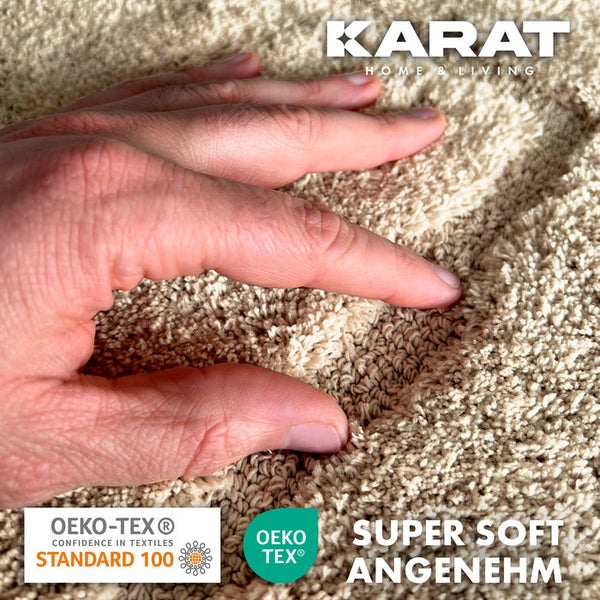Detailansicht eines beigen Teppichs mit der Hand einer Person, die die weiche Textur berührt, Karat Home and Living Logo, Oeko-Tex Standard 100 Siegel, Oeko-Tex Siegel, Super Soft Angenehm Siegel