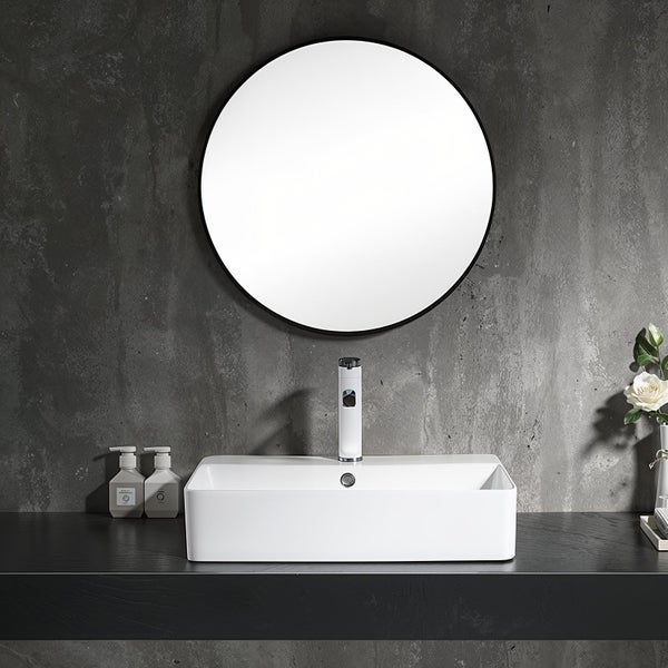Modernes Badezimmer mit weißem Aufsatzwaschbecken, einer elektronischen Armatur und einem runden Spiegel an einer strukturierten Wand.