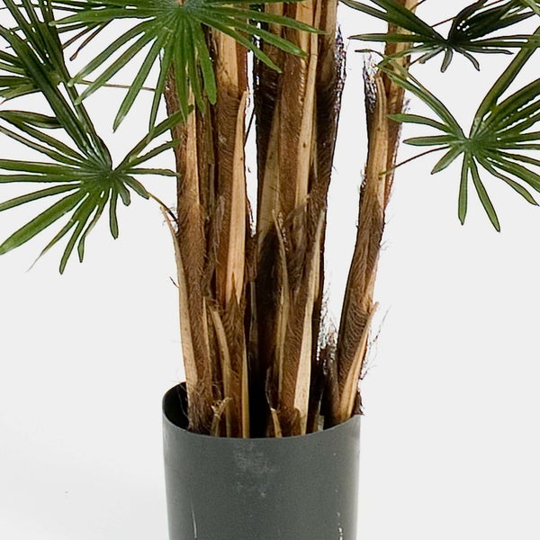 Künstliche Palme mit mehreren faserigen Stämmen und fächerförmigen Blättern in einem dunklen Topf.