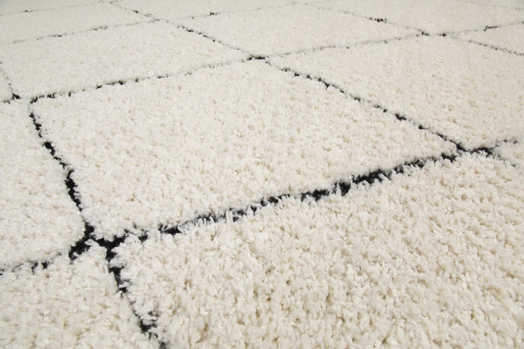 Hochflor-Teppich im Shaggy-Stil mit schwarzem Rautenmuster auf hellem Grund