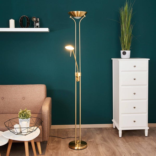 Messingfarbene Stehleuchte mit Deckenfluter und Lesearm in einem modernen Wohnzimmer mit Sofa, weißer Kommode und dunkler Wand.