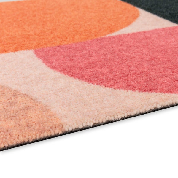 Nahaufnahme eines weichen Teppichs mit geometrischem Kreismuster in Orange, Pink und Creme.