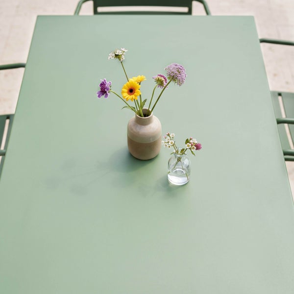 Rechteckiger Garten-Esstisch aus Metall mit zwei Vasen und bunten Blumen.