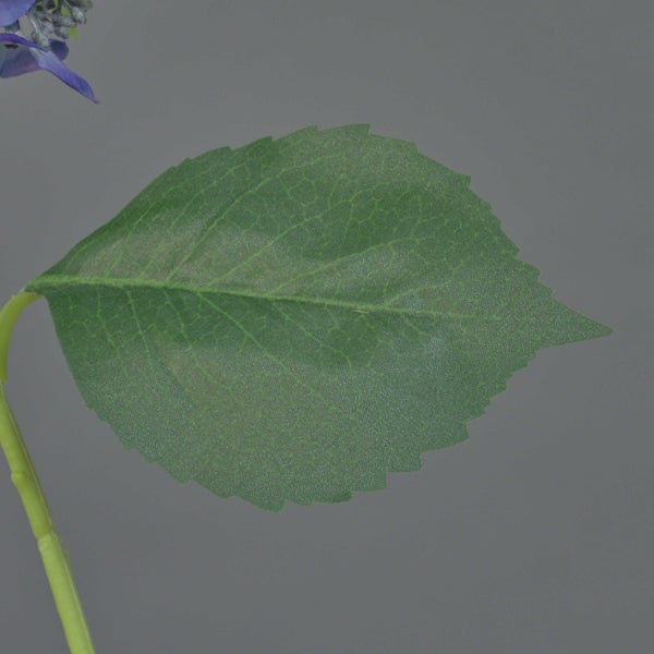 Nahaufnahme eines grünen Blattes einer Kunstpflanze mit gezacktem Rand und sichtbaren Blattadern.