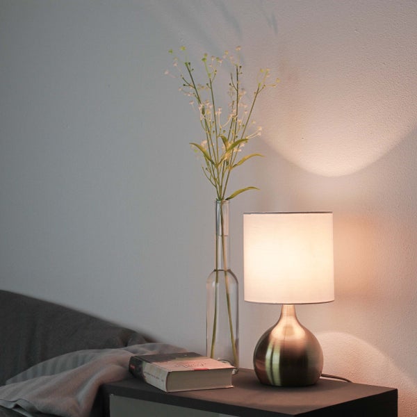 Nachttisch mit Lampe, Buch und Blumenvase