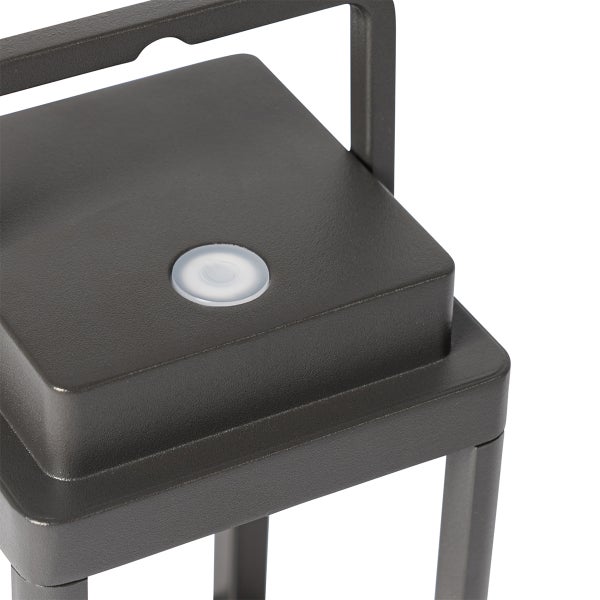 Detailansicht einer quadratischen Außenleuchte mit einem runden Einschaltknopf auf der Oberseite und einem Tragegriff.