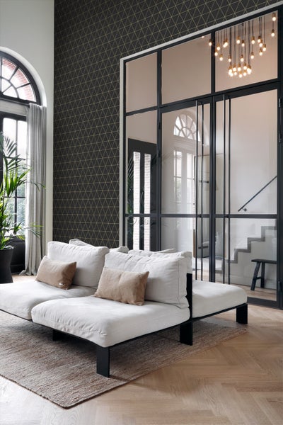 Wohnzimmer mit Sofa, Teppich und geometrischer Tapete