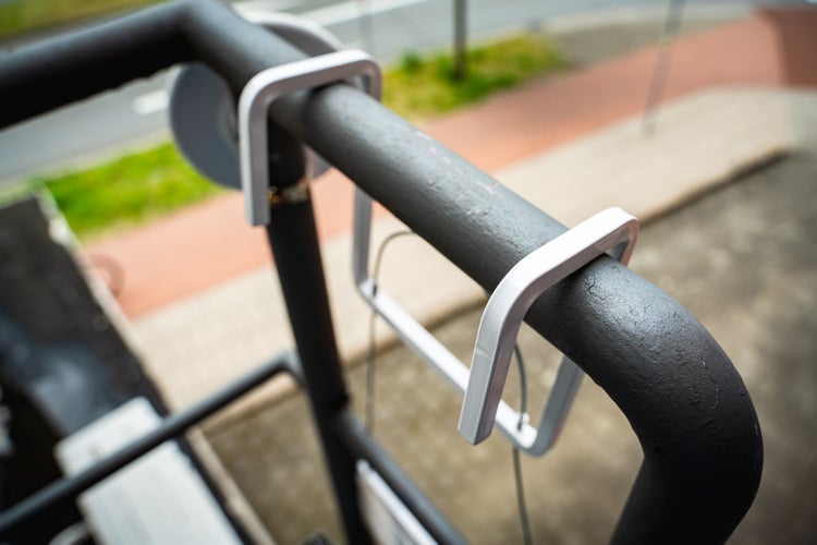 Detailaufnahme eines schwarzen Metallrohrs, das mit silberfarbenen Halterungen befestigt ist