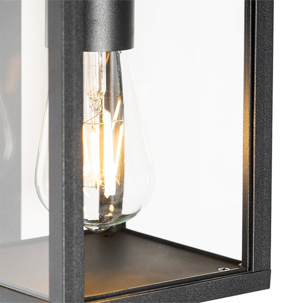 Nahaufnahme einer Außenleuchte mit Metallrahmen und Glaseinsätzen sowie einer leuchtenden Filament Glühbirne.