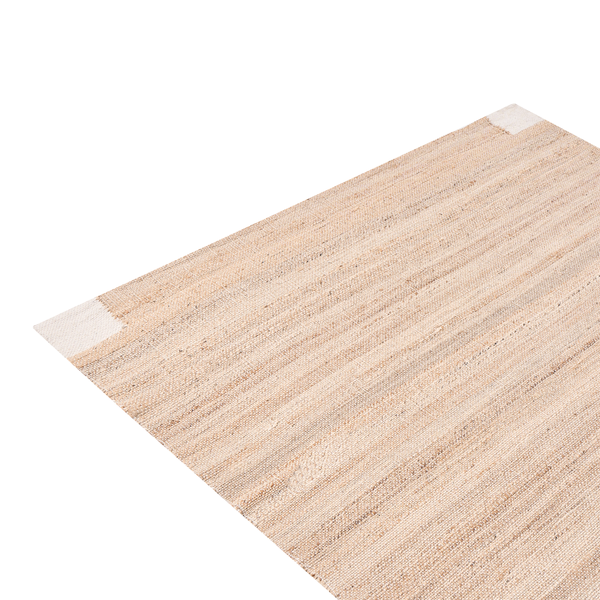 Moderner, heller Wohnraum mit Beistelltisch aus Glas auf einem Jute-Teppich, einem Bouclé-Sessel und einem Konsolentisch.