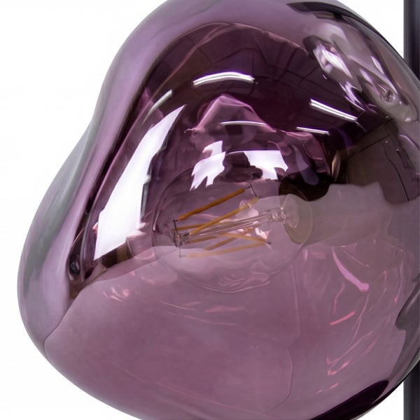 Nahaufnahme eines Leuchtenschirms aus unregelmäßig geformtem, violettem Glas mit sichtbarem LED-Leuchtmittel.