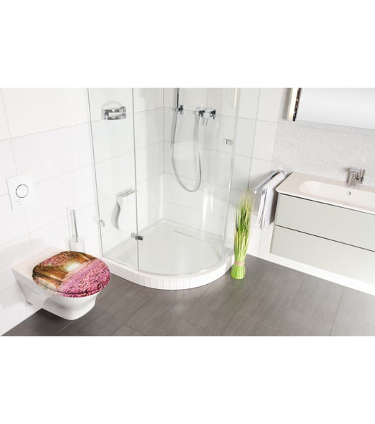 Modernes Badezimmer mit Hänge-WC inklusive Motiv-WC-Sitz, Glasduschkabine, hellem Waschtisch und grauen Bodenfliesen.