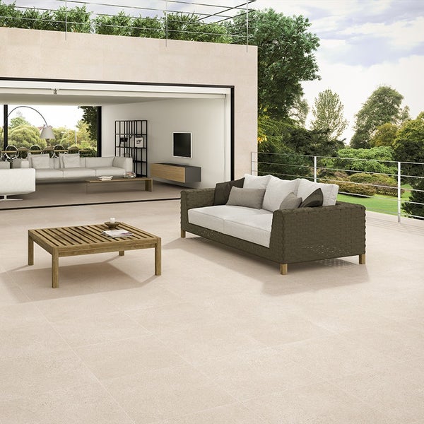Moderne Terrassenfliesen mit Natursteinoptik auf einer großzügigen Außenfläche vor einem offenen Wohnbereich mit Loungemöbeln.