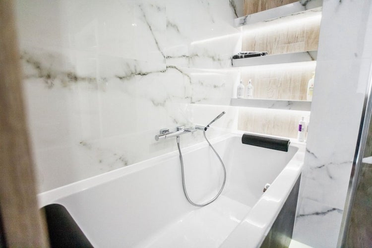 Badezimmer mit Badewanne, Armatur und Regalen