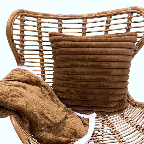 Rattansessel mit braunem Kissen und Decke