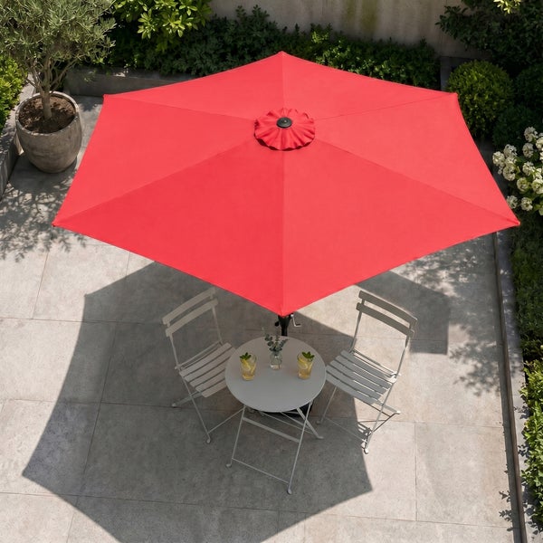 Roter Sonnenschirm über weißem Bistrotisch und zwei Klappstühlen auf einer gepflasterten Terrasse mit Pflanzen.