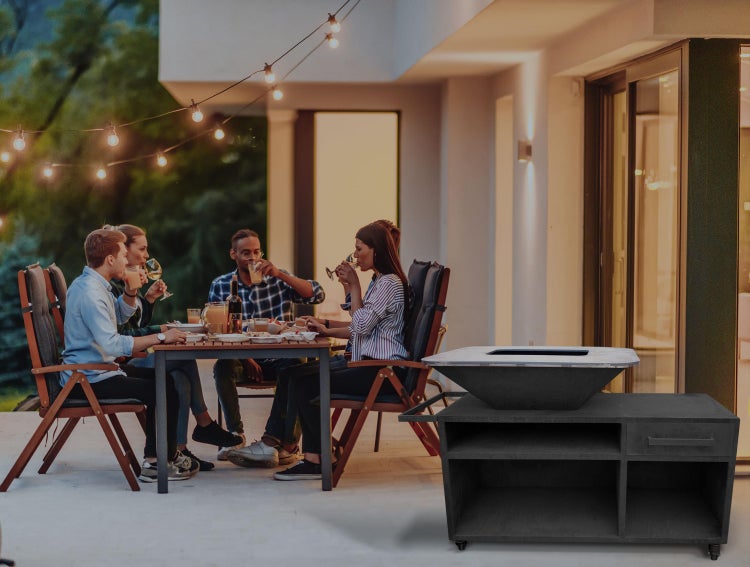 Szene im Freien mit einer Gruppe von Personen an einem Tisch und einem Feuerkorb auf einem rollbaren Unterschrank.