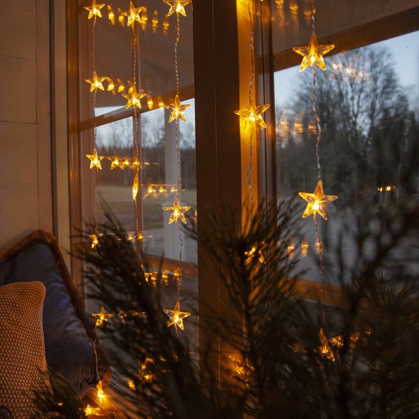 Dekoratives Fenster mit Sternenlichterkette für weihnachtliche Atmosphäre.