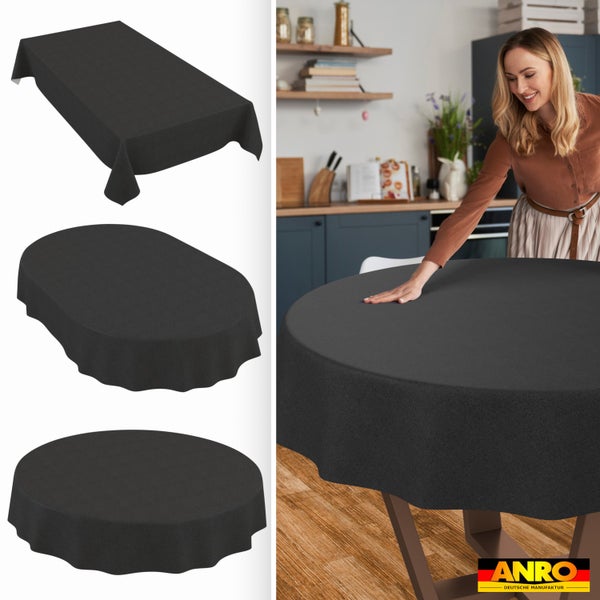 Dunkelgraue Tischdecke in rechteckiger, ovaler und runder Form. Eine Frau legt die runde Decke auf einen Küchentisch. ANRO Deutsche Manufaktur Logo.
