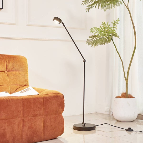 Schwarze Stehlampe neben Sessel und Zimmerpflanze