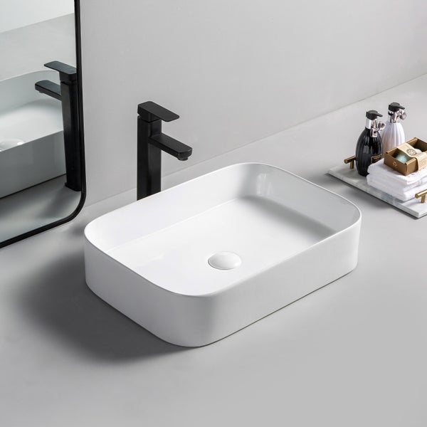 Rechteckiges weißes Aufsatzwaschbecken aus Keramik mit schwarzer Armatur und Spiegel in einem hellen, modern eingerichteten Badezimmer.
