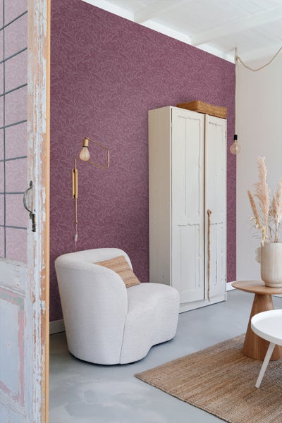 Wohnraum mit gemusterter Tapete, Sessel, Schrank und Beistelltischen