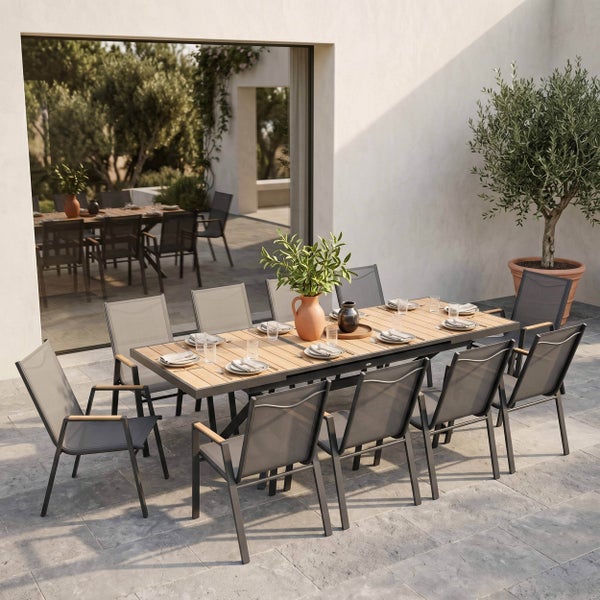 Gedeckter Gartentisch mit Holzlamellen, Metallgestell, Gartenstühlen, Geschirr, Besteck und Terrakotta-Krug in einer hellen Außenumgebung.