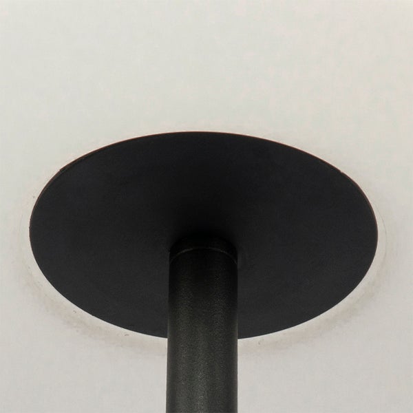 Detail einer schwarzen Lampenstange aus Metall mit runder Montageplatte.