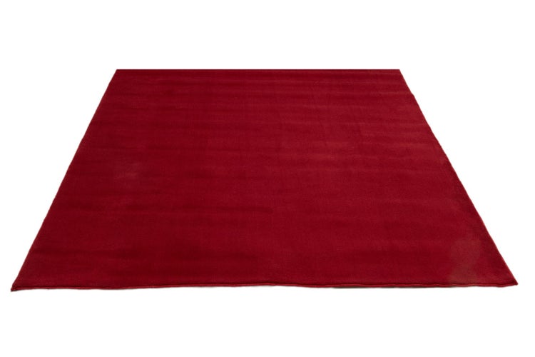 Rechteckiger roter Teppich mit weicher, samtiger Oberfläche.