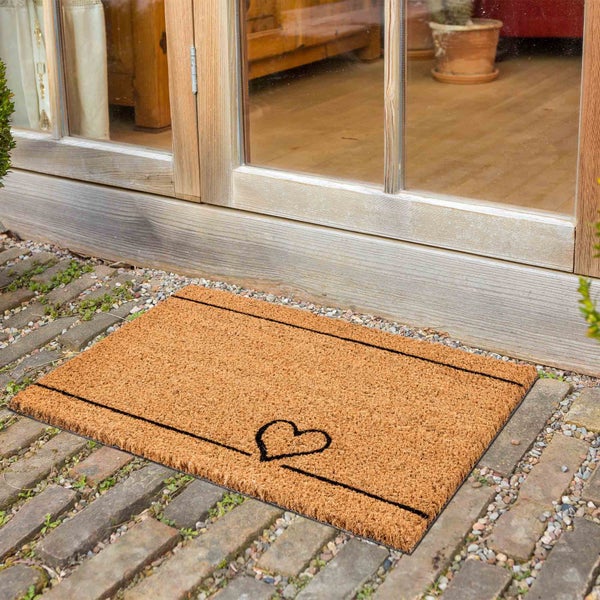 Fußmatte aus Kokosfaser mit Herzmotiv vor einer Tür
