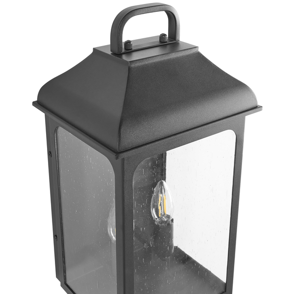 Außenwandleuchte in Laternenform aus Metall mit Blasenglas und sichtbarem Leuchtmittel.